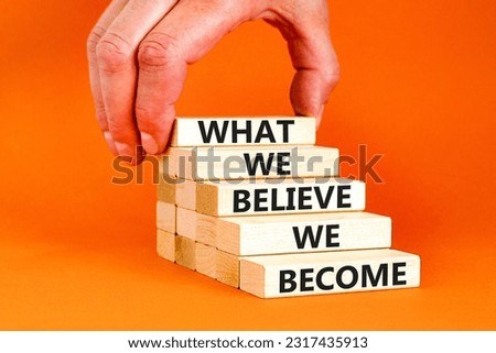 We become or believe symbol. Concept word What we believe We become on wooden block. Beautiful orange table orange background. Businessman hand. Business we become or believe concept. Copy space.
