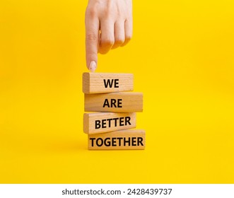 We are better together symbol. Wooden blocks with words We are better together. Beautiful yellow background. Businessman hand. We are better together concept. Copy space.