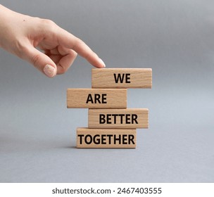We are better together symbol. Wooden blocks with words We are better together. Beautiful grey background. Businessman hand. We are better together concept. Copy space.