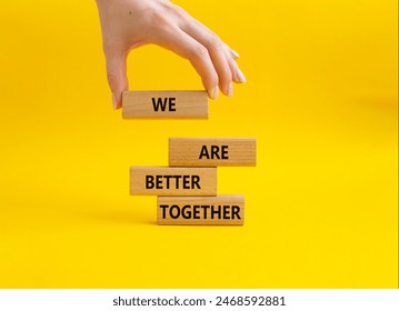 We are better together symbol. Wooden blocks with words We are better together. Beautiful yellow background. Businessman hand. We are better together concept. Copy space.