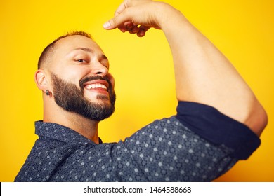 We Can Do It Concept. Close Up Portrait Of Charismatic 35 Years Old Man Posing Over Yellow Background, Showing His Bicep. Rolled Up Sleeves. Poster Style. Studio Shot