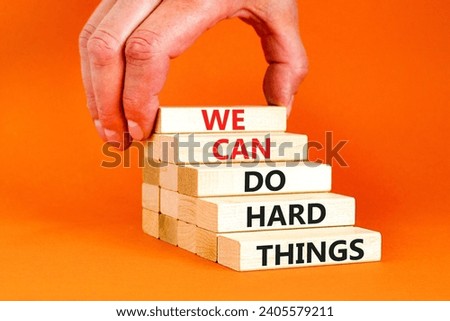 We can do hard things symbol. Concept words We can do hard things on wooden blocks. Beautiful orange table orange background. Businessman hand. Business, we can do hard things concept. Copy space.