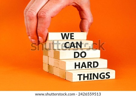 We can do hard things symbol. Concept words We can do hard things on wooden blocks. Beautiful orange table orange background. Businessman hand. Business, we can do hard things concept. Copy space.
