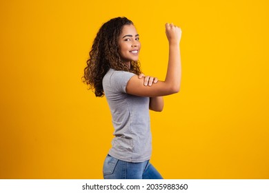 We Can Do It. Woman's Fist Of Female Power. Woman Victim Of Racism. Abuse At Work. The Feminine Power. Female Empowerment. The Strength Of Women. Yellow Background.
