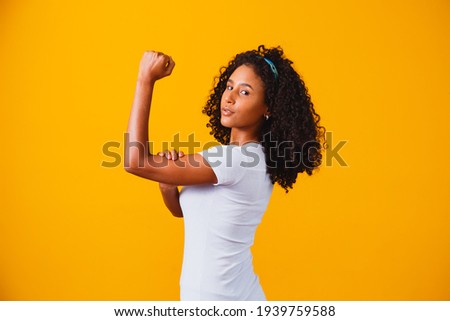 We can do it. Woman's fist of female power. Woman victim of racism. Abuse at work. The feminine power. Female empowerment. The strength of women. Yellow background.