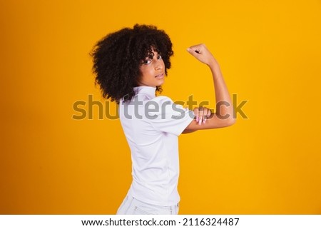 We can do it. Woman's fist of female power. Woman victim of racism. Abuse at work. The feminine power. Female empowerment. The strength of women. Yellow background.