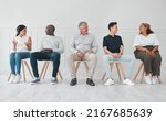 We can learn a lot by listening to each others stories. Shot of a diverse group of people talking to each other while sitting in line against a white background.