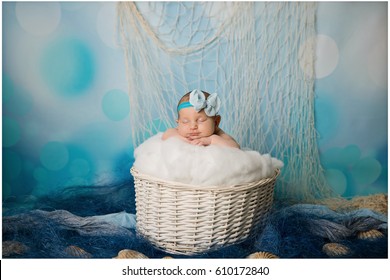 We can see a photo-shoot in a very sea-like style. A baby girl is sleeping in a white basket with a cotton wool.