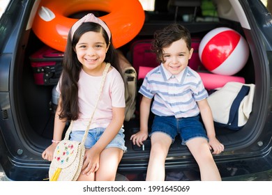 We Can't Wait To Get To The Beach. Adorable Little Brother And Sister Waiting For Their Parents In The Car While Packing Their Things To Start Their Family Vacations