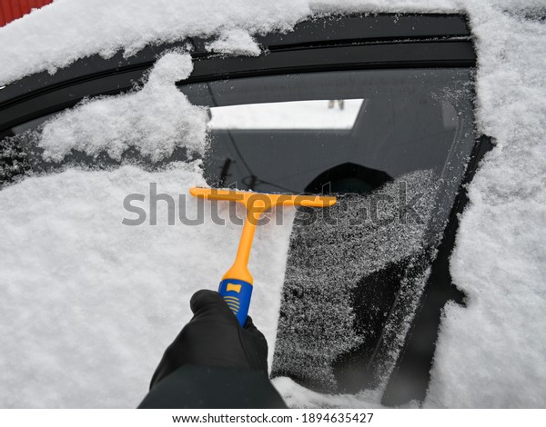 We clean\
the car from ice and snow with a scraper after a blizzard.\
Girl\
cleans the car windows of\
snow