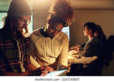 We Commit To Beat Every Deadline. Shot Of Two Coworker Discussing Something On A Digital Tablet While Working Night Shift At The Office.