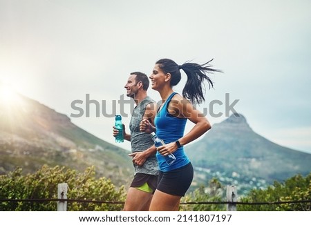 We compete in a friendly way. Shot of a young attractive couple training for a marathon outdoors.