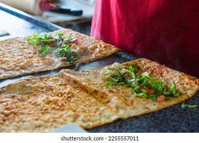 We cook shawarma step by step: a large round pita bread is spread with  chicken, salad and tomato on a wooden board. Cooking fast food. - Shutterstock ID 2255557011