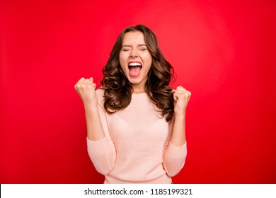 We did it! Portrait of closed eyes raised fists up woman in casual wear isolated on vivid red background with closed eyes and wide open mouth