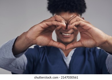 We Dont Just Think With Our Heads, We Think With Our Hearts. Shot Of A Male Nurse Forming A Heart Shape With His Hands While Standing Against A Grey Background.