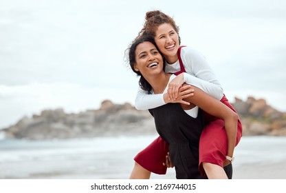 We Dream In Colors Borrowed From The Sea. Shot Of A Woman Giving Her Friend A Piggy Back Ride.