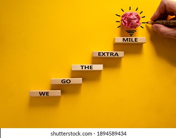 We go the extra mile symbol. Wood blocks stacking as step stair on beautiful yellow background, copy space. Male hand, light bulb. Words 'We go the extra mile'. Business and go the extra mile concept.
