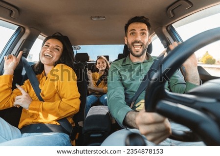 We are going on vacation. Happy family of three driving in their automobile, dancing to music and singing favorite song, enjoying travelling by car