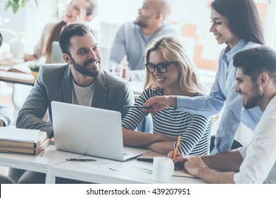 We got great results! Group of young cheerful business people working and communicating while sitting at the office desk together with colleagues sitting in the background  - Shutterstock ID 439207951