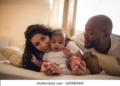  We Are Happy Family. African American Parents With Daughter On Bed.