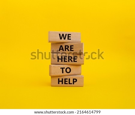 We are here to help symbol. Concept words we are here to help on wooden blocks. Beautiful yellow background. Business and we are here to help concept. Copy space.