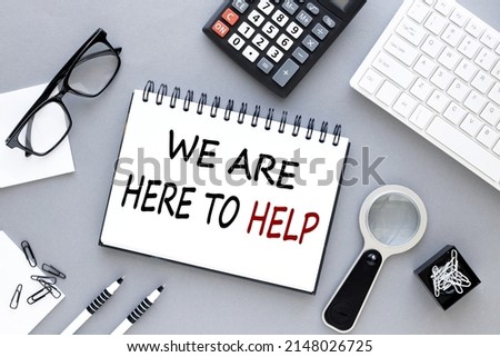 we are here to help. text on open notepad on gray background near white keyboard calculator