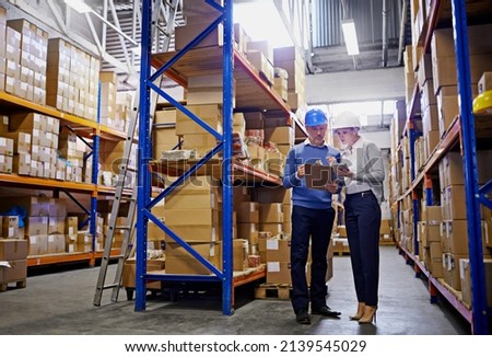 We know where every order is in this warehouse. Shot of a man and woman inspecting inventory in a large distribution warehouse.