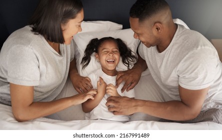 We Know Your Weak Spot. Shot Of A Young Couple Sitting In Bed And Bonding With Their Daughter By Tickling Her.