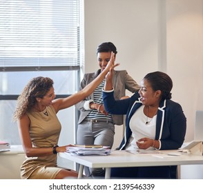 We Make An Awesome Team. Shot Of A Group Of Female Colleagues High Fiving Together In An Office.