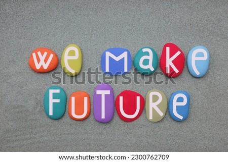 We make future, creative slogan composed with multi colored stone letters over green sand