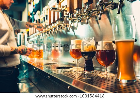 We meet oktoberfest. Hand of bartender pouring a large lager beer in tap. Pouring beer for client. Side view of young bartender pouring beer while standing at the bar counter