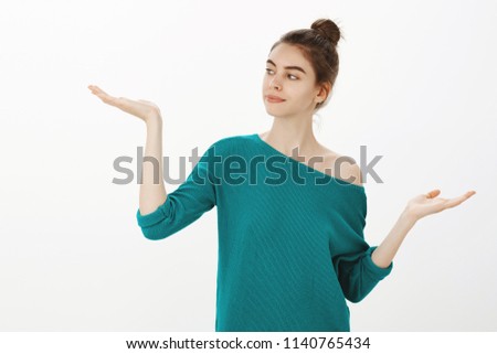 We need to make decisions. Portrait of cute good-looking woman with bun hairstyle in stylish loose sweater holding palms up in weighing gesture, making choice and look at opportunities