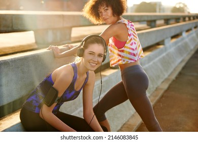 We prepare differently before a run. Portrait of a young female jogger listening to music before a run with a friend through the city.