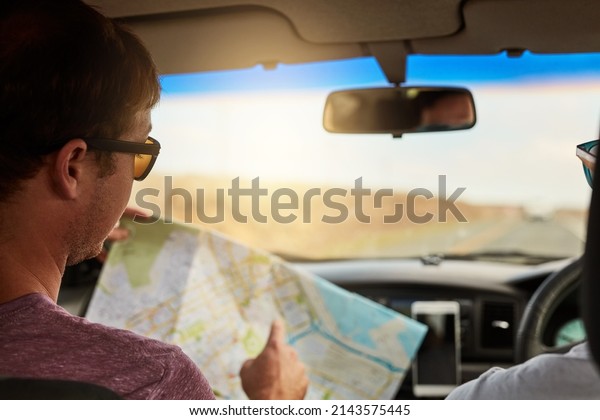 We should reach this destination in\
twenty minutes. Shot of two young friends reading a map while\
driving in their vehicle and heading to their\
destination.