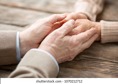 We are together. Close up of hands of a pleasant nice aged man holding his wifes hands