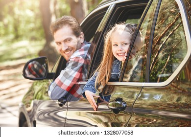 We Travel Not To Escape Life, But For Life Not To Escape Us. Father And Daughter Looking Out The Car Window. Girl Smiling Happily At The Camera. Family Road Trip