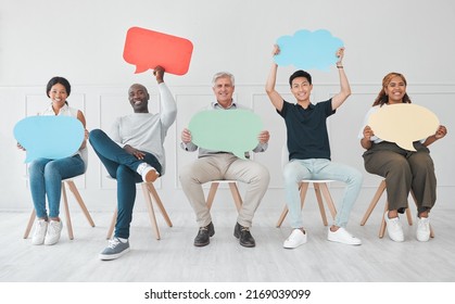 We want our opinions to be heard as well. Portrait of a diverse group of people holding colourful speech bubbles while sitting in line against a white background.