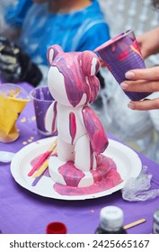 We water the plaster figurine of the bear with paints of various colors. Creativity for children.