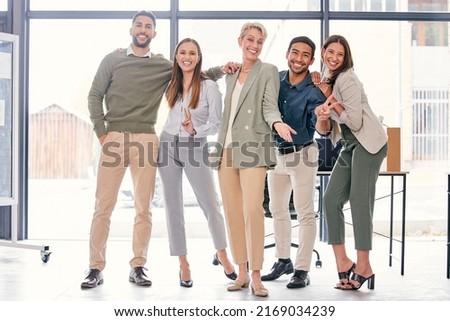 We work hard and have fun too. Full length shot of a diverse group of businesspeople standing together and feeling playful in the office.