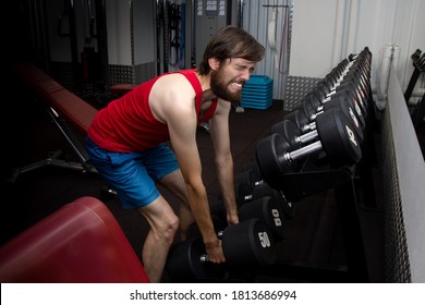 Weak Man Tries To Lift Heavy Dumbbell, Wants To Be Strong And Fit. Sport, Motivation, Strength. Newbie Concept In The Gym.