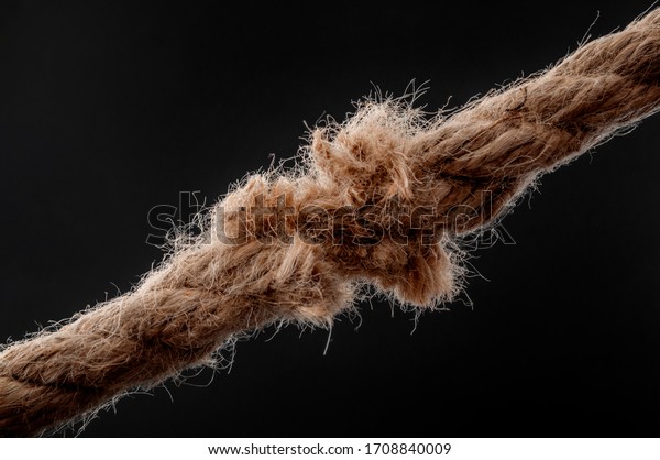 Weakness, vulnerability and single point\
of failure concept with worn rope string  breaking under physical\
stress pulling on it isolated on black\
background
