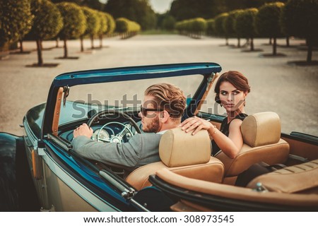 Wealthy couple in a classic convertible 