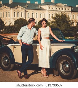 Wealthy Couple Near Classic Convertible Against Royal Palace 