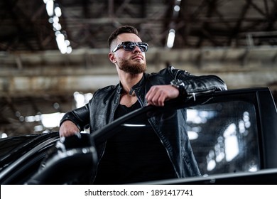 Wealthy Life Of Young Man. Cool Brutal Man Near Luxury Black Brend Car. Total Leather Black Outfit On Man.