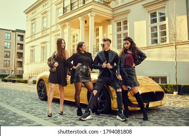 A wealthy man in a golden car surrounded by women. The man is all in gold, is popular with girls. Friends came to a party at the cottage. A man surrounds women.