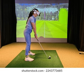 Wear virtual reality goggles and play golf. Golf indoor simulator - Shutterstock ID 2243773685