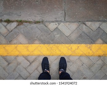 Wearing black shoes, standing brfore the straight yellow line on the concrete floor. Concept: Do/Do not cross the line, step forward, move on. - Shutterstock ID 1541924072