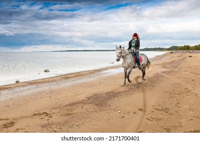 Wearing Jeans, Jacket And Fall Hat Female Horseback Raider Gallops A Dappled Hackney Along Seaboard