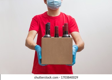 ?ourier Wearing Protective Mask And Gloves Holding Box With Bottles Of Wine. Safe Online Wine Store Delivery During Quarantine.