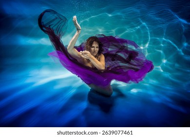 wearing in a purple dress lass is undersea in the swimming pool